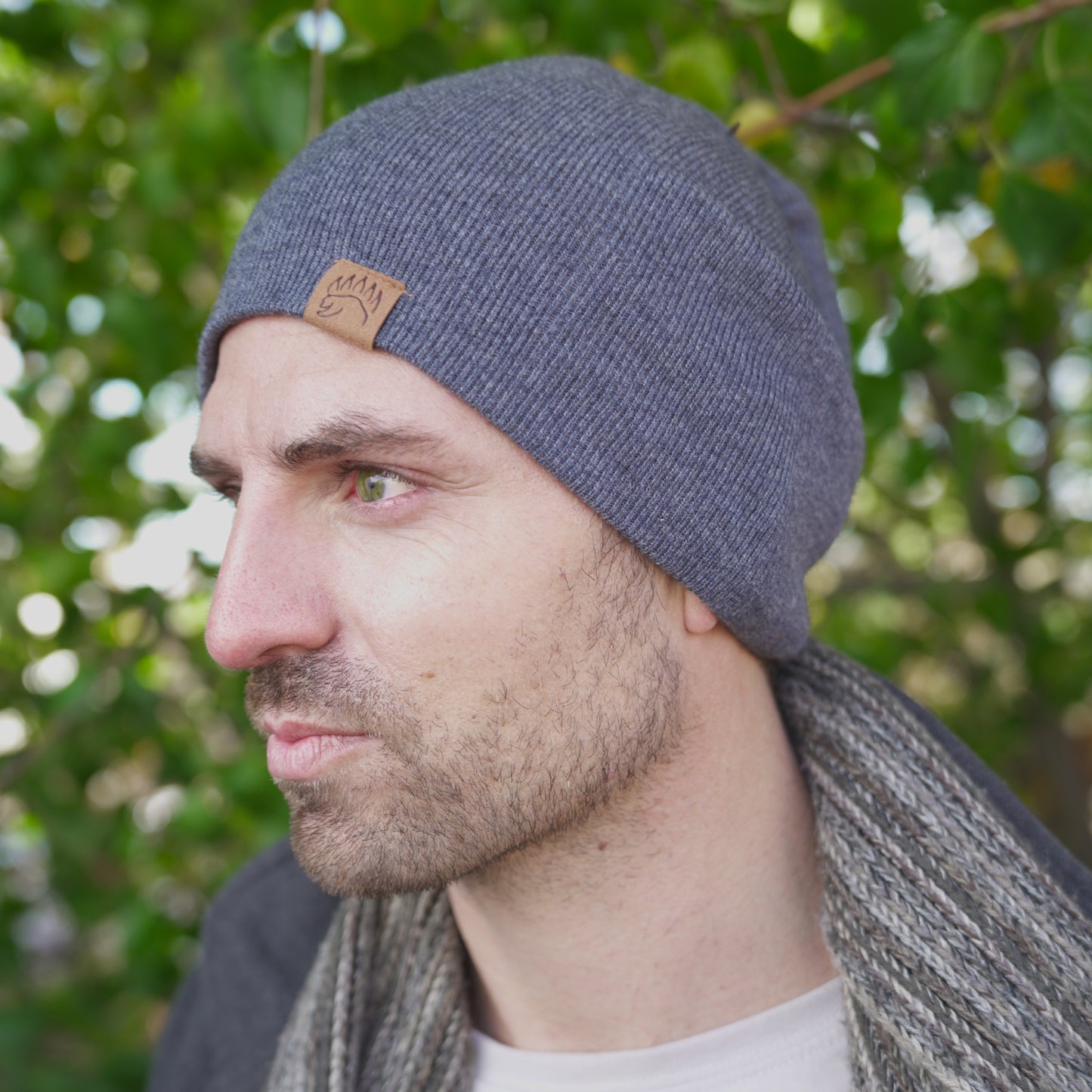 Side view of man in charcoal 100% Soft Merino Wool Beanie with ribbed texture and bear paw logo, perfect for winter warmth.
