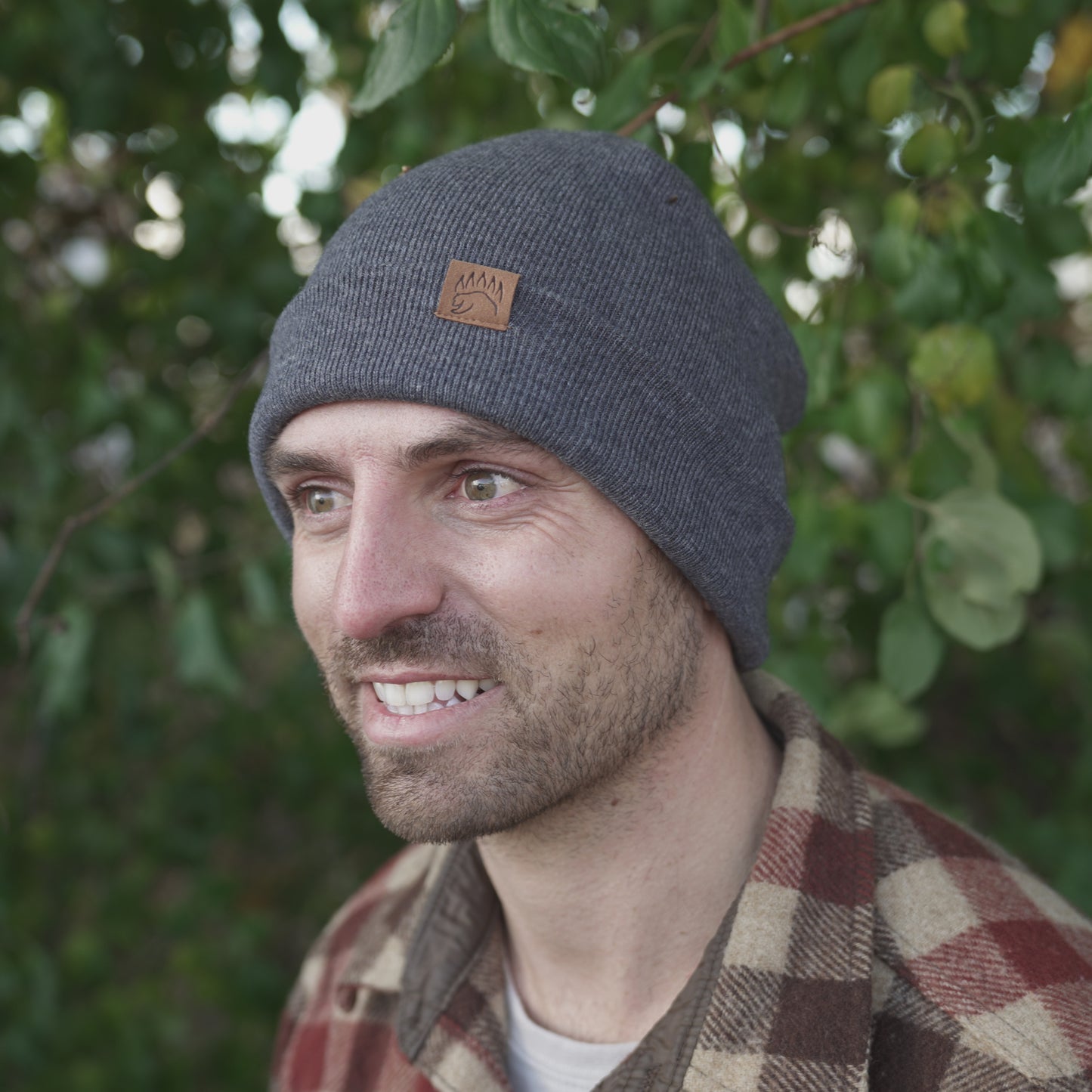 Man wearing charcoal 100% Soft Merino Wool Beanie with bear paw logo, ideal for cold weather and outdoor adventures.