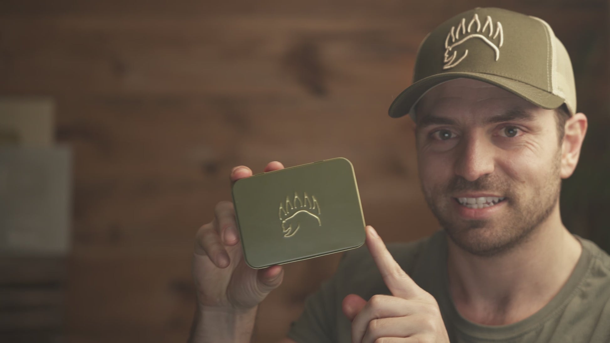 Man holding The Bear Essentials Knot Tying Kit tin, showcasing compact design ideal for outdoor and camping knot learning.